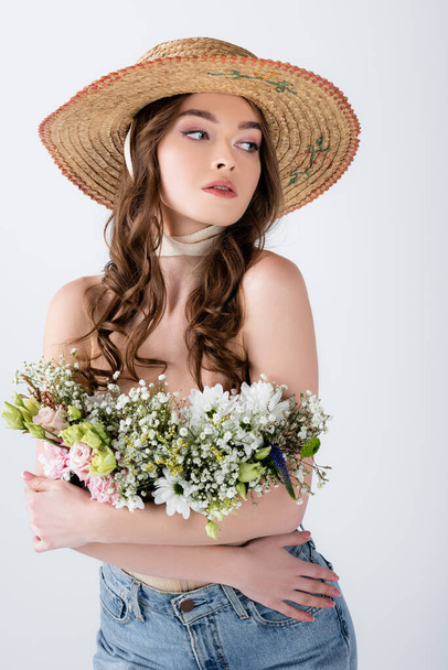 Curly woman in sun hat and flowers in blouse posing isolated on grey  - Fotó, kép