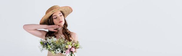 Young woman in stylish straw hat with flowers in blouse standing with closed eyes isolated on grey, banner  - Foto, Bild