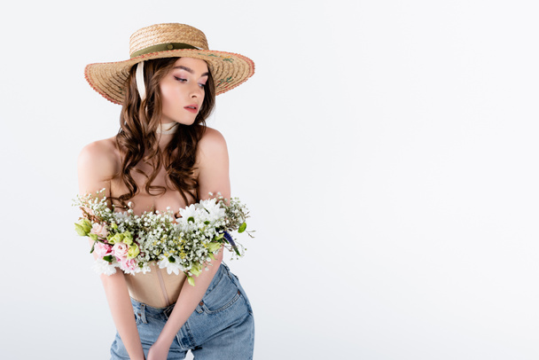 Modelo com flores em blusa posando em chapéu de sol isolado em cinza  - Foto, Imagem