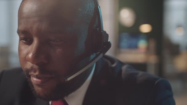 Στήθος μέχρι πλάνο του επαγγελματία μαύρου επιχειρηματία σε ακουστικά συζητώντας την εργασία σε απευθείας σύνδεση βιντεοκλήση στο γραφείο - Πλάνα, βίντεο