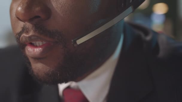 オフィスでオンライン通話で話す無線ヘッドセットで黒人ビジネスマンの顔の下の部分のショットを閉じます - 映像、動画