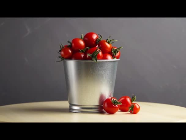 Tahta bir masanın üstünde, bir kova taze kırmızı kiraz domatesinin etrafında dönüyor. Yan görüş. Hasat et. Doğal yiyecek.. - Video, Çekim