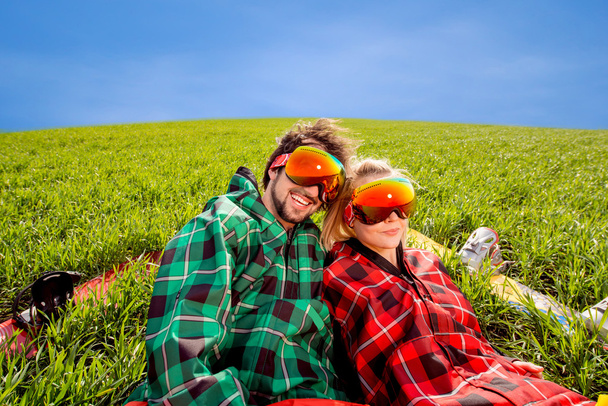Пара в спортивной одежде со сноубордами, лежащими на траве
 - Фото, изображение