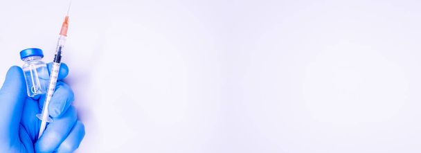 Coronavirusgriep en pandemische vaccins, spuit en injectieflacon met rode vloeistof op een blauwe achtergrond. medisch concept, stethoscoop, subcutane injectie, behandeling van de ziekte. Kopieer ruimte voor tekst of logo Kopieer ruimte - Foto, afbeelding