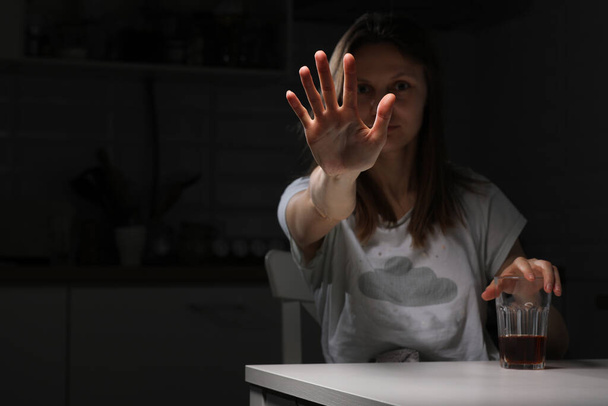 Депрессивная грустная молодая женщина чувствует себя плохо пить виски в одиночестве дома, показывая руку остановить алкоголь, алкоголик страдает от алкогольной зависимости, имеющих проблемы, концепция алкоголизма - Фото, изображение