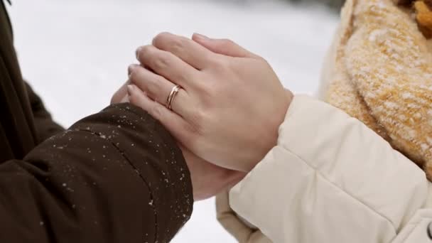 Крупный план рук неузнаваемых людей, согревающих руки друг друга на улице в зимний снежный день - Кадры, видео