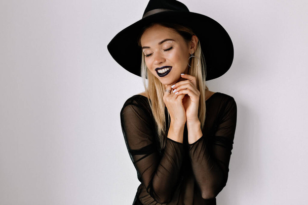 Charming tenderness woman with blond hair and holiday make up wearing hat and black blouse posing over isolated background. High quality photo - Photo, Image