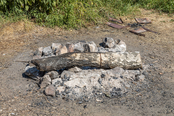 Οι γκρι και καφέ μεγάλες πέτρες και κορμό σημύδας για μια φωτιά είναι σε ένα τζάκι στο δάσος - Φωτογραφία, εικόνα