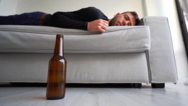 П'яний молодий чоловік з пляшкою пива спить на дивані вдома
. - Кадри, відео