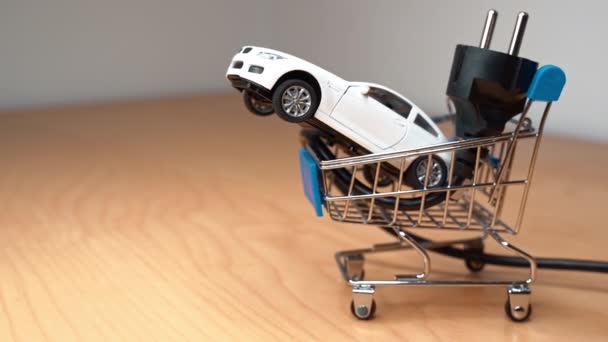 Coche de juguete y enchufe eléctrico dentro de un pequeño carrito de compras - Imágenes, Vídeo