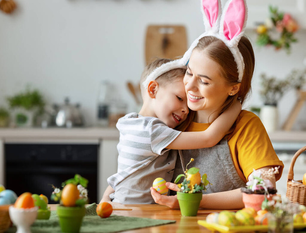 Joyeux Pâques ! famille : mère et enfant fils avec des oreilles lièvre se préparer pour les vacances, peindre des œufs dans la cuisine confortable à la maison - Photo, image