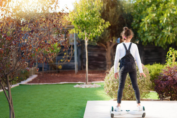 Visão traseira da menina montando uma scooter elétrica ao ar livre. Jovem adolescente equilibra no Hoverboard. - Foto, Imagem