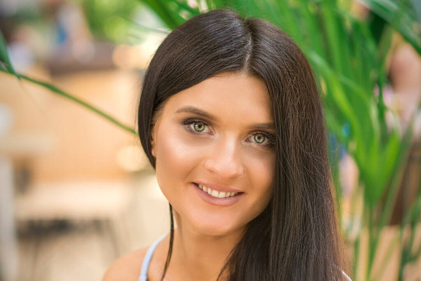 Πορτρέτο μιας όμορφης νεαρής χαμογελαστής καυκάσιας γυναίκας που κοιτάζει την κάμερα σε εξωτερικούς χώρους - Φωτογραφία, εικόνα