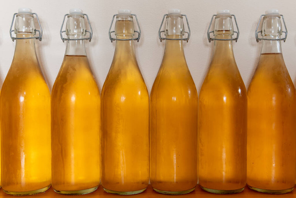 Primer plano de una fila de botellas flip top de sidra casera cubierta de condensación - Foto, Imagen
