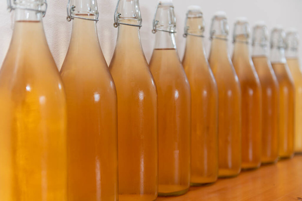 Close-up van een rij flip-top flessen zelfgemaakte cider bedekt met condensatie - Foto, afbeelding