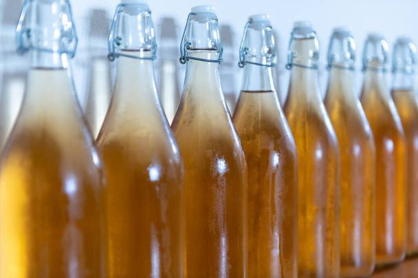 Close-up de uma fileira de garrafas de topo de virar de cidra caseira coberta de condensação - Foto, Imagem
