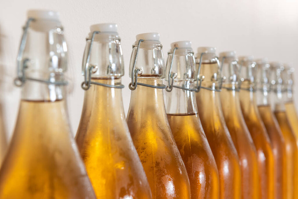Nahaufnahme einer Reihe von Flip-Top-Flaschen hausgemachten Cider, die mit Kondenswasser bedeckt sind - Foto, Bild