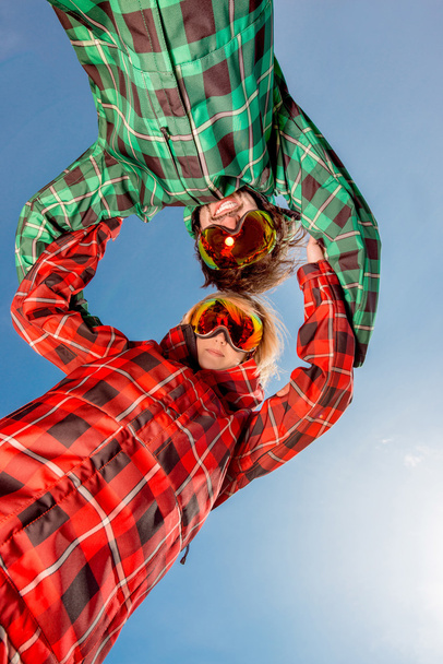 пара в лыжных костюмах в солнечных очках, держась за руки на голубом небе
 - Фото, изображение