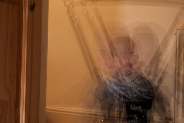 Mehrfachbelichtung an einem kaukasischen Jungen auf dem Jumper Baby Exerciser. Mittenschuss im Haus. - Foto, Bild