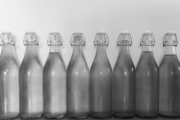 Foto en blanco y negro de una fila de botellas flip top de sidra casera cubierta de condensación - Foto, Imagen