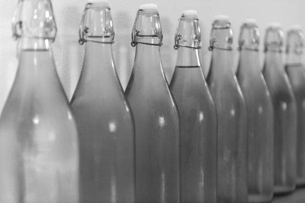 Ασπρόμαυρη φωτογραφία μιας σειράς από μπουκαλάκια σπιτικού μηλίτη καλυμμένα με συμπύκνωση - Φωτογραφία, εικόνα