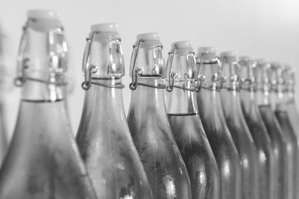 Черно-белое фото ряда флип-топ бутылок самодельного сидра, покрытых конденсатом - Фото, изображение