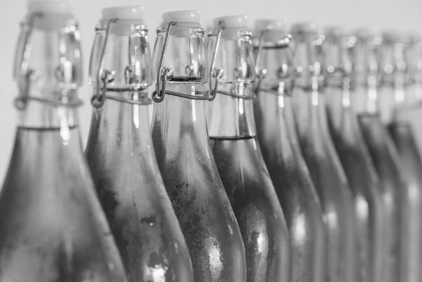 Foto em preto e branco de uma fileira de garrafas de topo de virar de cidra caseira coberta de condensação - Foto, Imagem