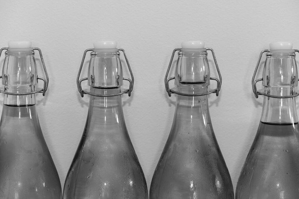 Foto en blanco y negro de una fila de botellas flip top de sidra casera cubierta de condensación - Foto, imagen