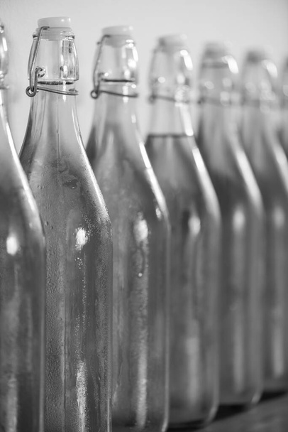 Bir sıra ev yapımı elma şarabı şişesinin yoğunlaştırılmış siyah beyaz fotoğrafı. - Fotoğraf, Görsel