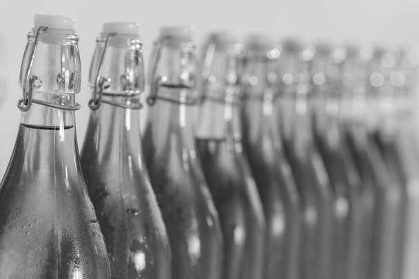 Photo en noir et blanc d'une rangée de bouteilles de cidre fait maison recouvertes de condensation - Photo, image