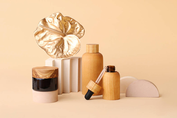 Beautiful composition from the cosmetics bottles and golden flamingo flower.Neutral beige colors, zero waste containers.Photography with copy space, good for advertising.Trendy geometrical podiums near. - Фото, изображение