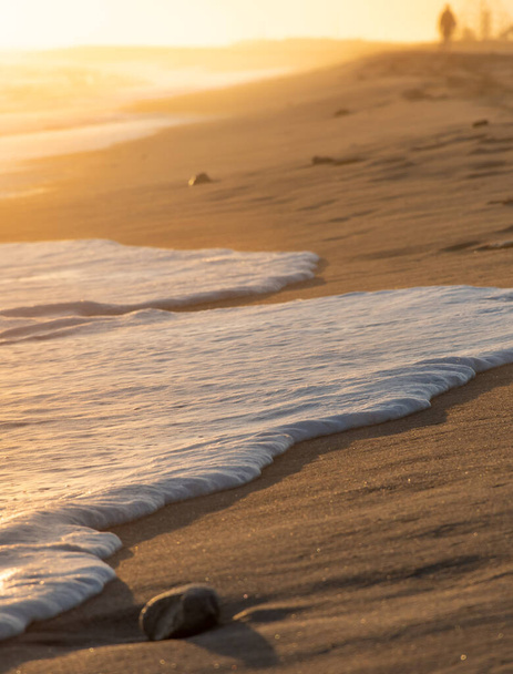 vague se brisant sur le sable de la plage formant de la mousse blanche - Photo, image