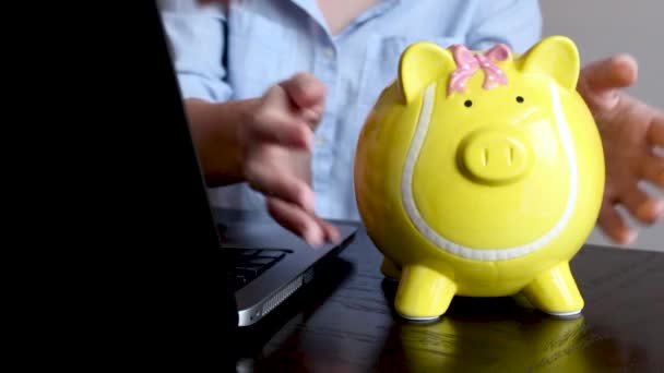 Woman taking money from piggy bank at table, closeup. Slow motion effect - Footage, Video