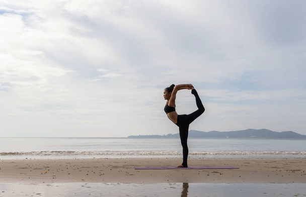 femme pratiquant le yoga pendant le coucher de soleil surréaliste au bord de la mer. concept sain et entraînement. - Photo, image