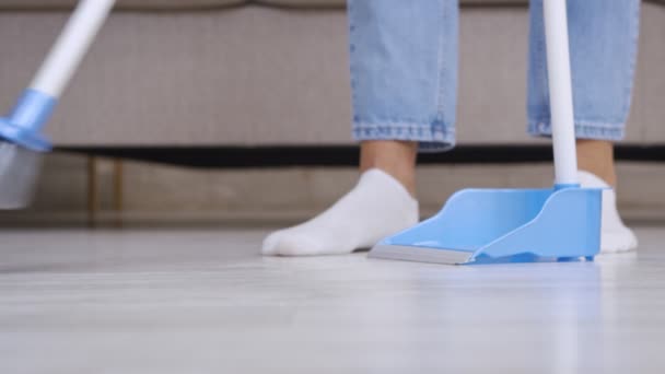 Domácí rutina. Detailní záběr ženy zametající podlahu doma s koštětem a lopatkou, zpomalený pohyb - Záběry, video