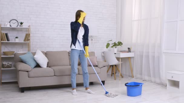 Fárasztó házimunka. Fiatal fáradt nő tart szünetet tavaszi takarítás otthon, törli a homlokát - Felvétel, videó