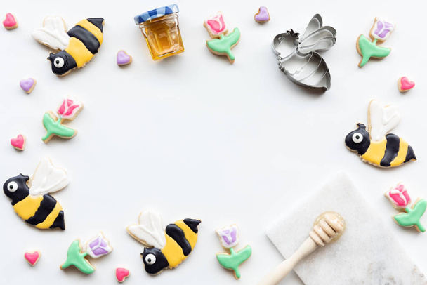 Vue du haut vers le bas d'une bordure de biscuits au sucre en forme d'abeilles, de tulipes et de coeurs. Un concept printemps et été. - Photo, image