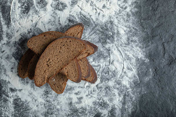 Vue du dessus du pain brun tranché sur fond de farine - Photo, image