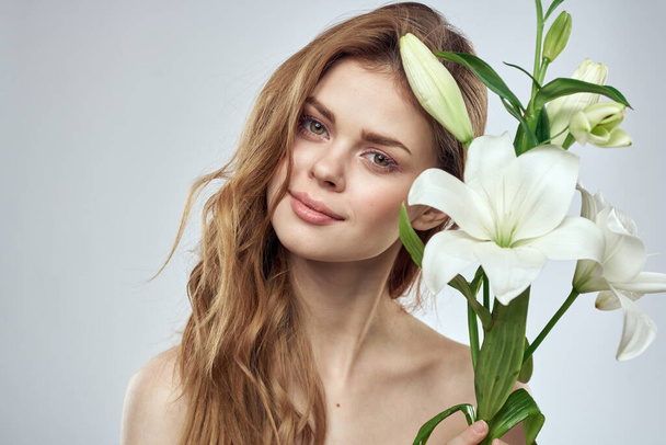 meisje met bloemen bijgesneden uitzicht portret close-up lente kale schouders heldere huid make-up - Foto, afbeelding