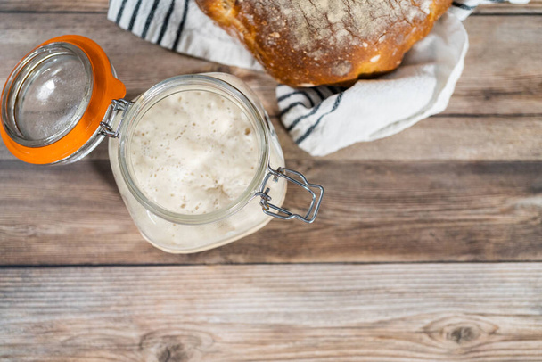 Nutrire l'antipasto di pasta madre in un barattolo di vetro per cuocere il pane artigianale. - Foto, immagini