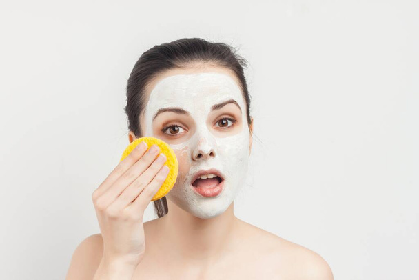 Cheerful brunette wipes face mask with sponges cropped view - Photo, Image