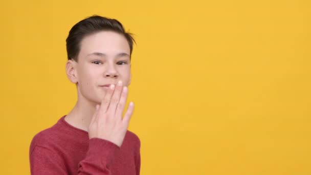 Εφηβικό αγόρι φυσάει φιλί στην κάμερα ποζάροντας στο κίτρινο φόντο - Πλάνα, βίντεο