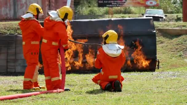 防火性との消防士の戦い。消防士は、火災の操作から保護するためのハード帽子、ボディセーフスーツの制服を着用してください。消火器で訓練された救助危険な火災 - 映像、動画