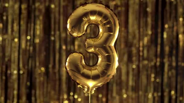 Gold foil number 3 three festive balloon on a yellow background. The concept of birthday, anniversary, date. - Footage, Video
