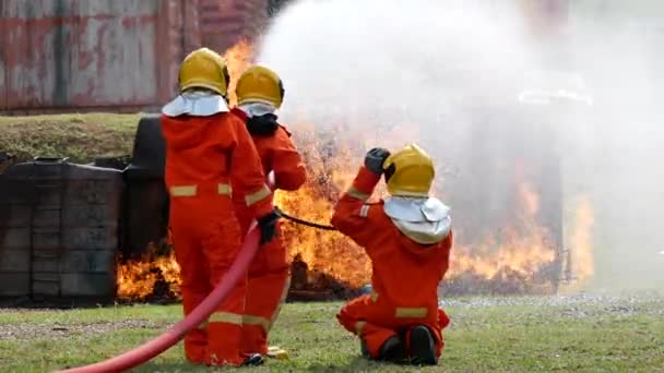 防火性との消防士の戦い。消防士は、火災の操作から保護するためのハード帽子、ボディセーフスーツの制服を着用してください。消火器で訓練された救助危険な火災 - 映像、動画