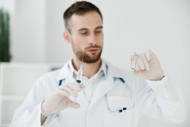 lékař drží ampulku s vakcínou v ruce, lékařský plášť a ochranné rukavice - Fotografie, Obrázek