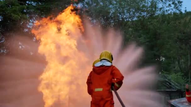 Palomies taistelee palo liekki suojaa omaisuutta. Palomies käyttää kypärää, kehon turvapuku yhtenäinen suojaa palo toimintaa. Pelastuskoulutus palonsammuttimien vaarallisissa paloissa - Materiaali, video