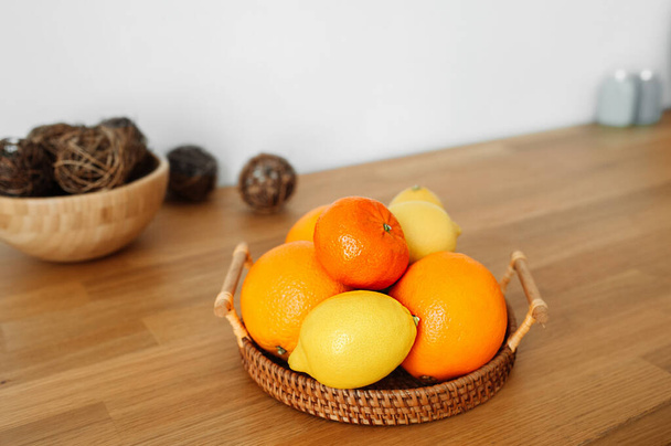 paljon sitrushedelmiä appelsiinit, mandariinit ja sitruunat puinen paju eko tarjotin kirkkaassa puinen keittiö. terveellinen ravitsemus ja linnoitus, valikoiva keskittyminen - Valokuva, kuva
