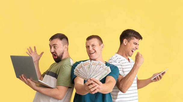 Hommes heureux après la victoire de leur pari sportif sur fond de couleur - Photo, image