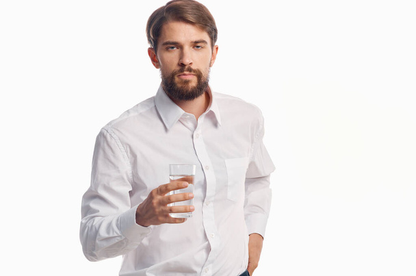 hombre guapo con vaso de agua estilo de vida saludable camisa blanca fondo claro - Foto, imagen